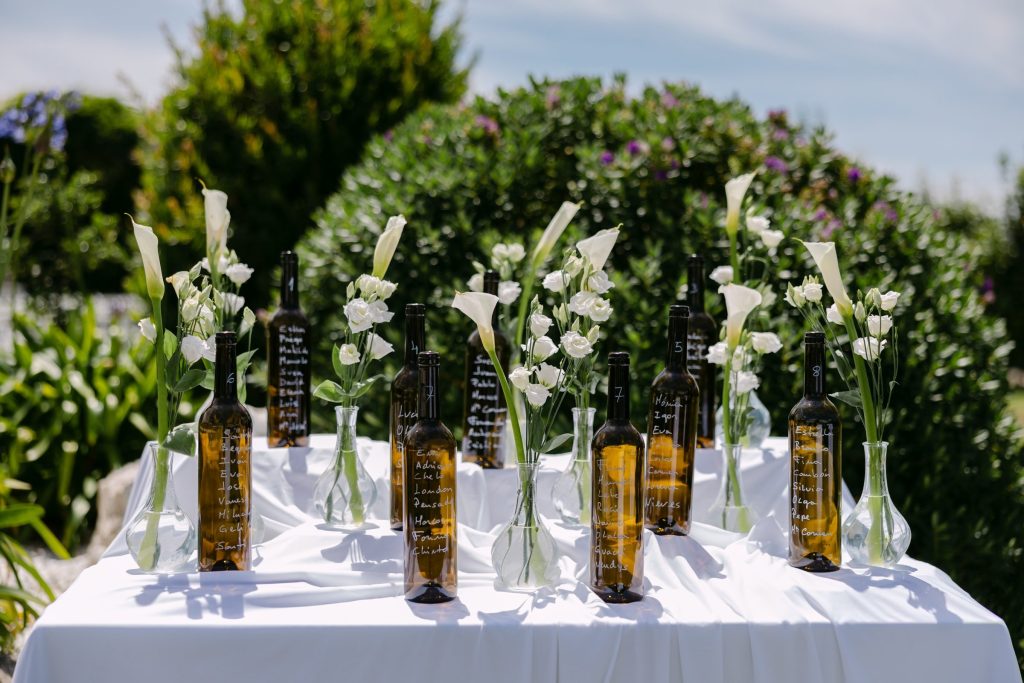 Seating plan con botellas y flores blancas en una boda en Galicia